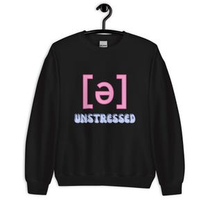 May include: Black sweatshirt with the word "UNSTRESSED" in light blue, and a pink phonetic symbol. The sweatshirt is hanging on a black hanger.
