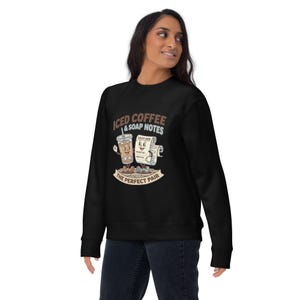 May include: Black sweatshirt with a graphic of an iced coffee and a soap notes sheet, both with smiling faces. The text reads "ICED COFFEE & SOAP NOTES" and "THE PERFECT PAIR" in a vintage style.