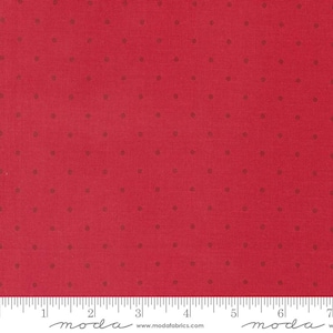 May include: Red fabric with small, evenly spaced brown dots. The fabric has a textured appearance and a ruler is visible along the bottom edge. The fabric is likely used for quilting or other sewing projects.