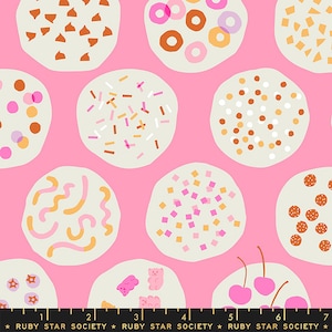 May include: Pink fabric with a repeating pattern of white circles with various colorful toppings, including sprinkles, chocolate chips, gummy bears, and cherries. The fabric has a black and white ruler printed at the bottom with the text "RUBY STAR SOCIETY".