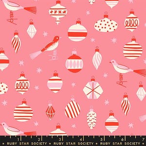 May include: A pink fabric featuring a repeating pattern of white and red Christmas ornaments, stylized birds, and small stars. The bottom edge includes a black selvage strip with the repeating white text "RUBY STAR SOCIETY" and a ruler.