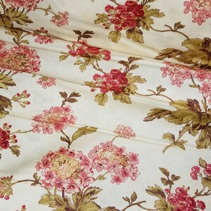 May include: A cream-colored fabric with a floral pattern. The flowers are pink and red with brown leaves.