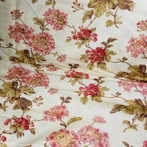 May include: A cream-colored fabric with a floral pattern. The flowers are pink and red with green leaves.