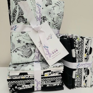 May include: A stack of black and white fabric squares with a zebra print and other geometric patterns. The fabric is wrapped with a white ribbon and a tag that says "Free Spirit" with a website address.