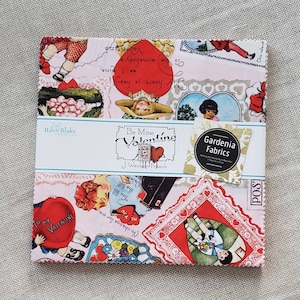 May include: A pink and white fabric with a Valentine's Day theme. The fabric features a variety of vintage-style illustrations, including hearts, flowers, and children. The fabric is trimmed with a white lace border. The text "Be Mine Valentine" is printed on a white label attached to the fabric. The text "Gardenia Fabrics" is printed on a white label attached to the fabric.