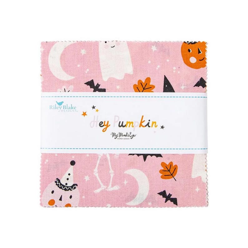 May include: A stack of pink fabric squares with a Halloween theme. The fabric features white ghosts, pumpkins, bats, and moons. The text "Hey Pumpkin" is printed on a white band across the center. The brand name "Riley Blake Designs" is also visible.