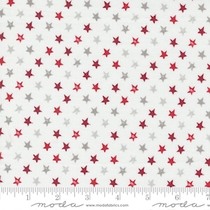 May include: White fabric with a repeating pattern of red and gray stars. The fabric is marked with a ruler in inches and the words "moda" and "www.modafabrics.com".