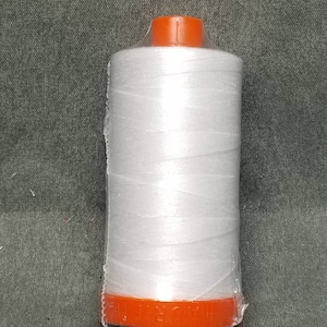 May include: A white spool of thread wrapped in clear plastic with an orange plastic cap.