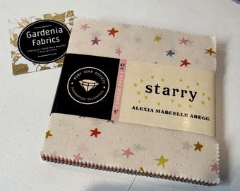 May include: A 42-piece 5-inch charm pack of fabric squares by Ruby Star Society titled Starry by Alexia Marcelle Abegg. The fabric features a cream background with small multi-colored stars in red, yellow, pink, and blue. A Gardenia Fabrics card is included.