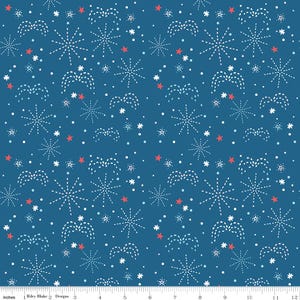 May include: A seamless pattern on a blue background featuring white and red starbursts, stars, and dotted lines. The design includes various sizes of starbursts and stars, creating a festive and celebratory feel. The text "Riley Blake Designs" is visible.
