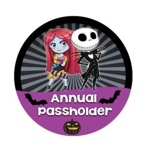 May include: A purple and black round sticker with a cartoon image of Jack Skellington and Sally from the Nightmare Before Christmas. The sticker says "Annual Passholder" and has a pumpkin graphic.