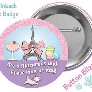 May include: A 3-inch pinback park badge with a pink and purple background. The badge features a cartoon illustration of the Eiffel Tower, macarons, a glass of frosé, and a white cat. The text on the badge reads "It's a Macarons and Frose kind of day!"