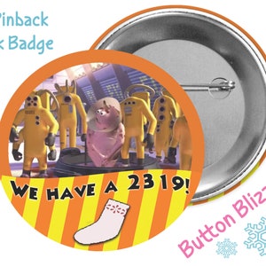 May include: A 3-inch pinback button with an orange and yellow striped background. The button features a cartoon image of a pink creature with a group of yellow figures in the background. The text "We have a 2319!" is printed on the button. A pink sock with a white flower design is in the lower right corner of the button.