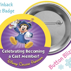 May include: A 3-inch pinback park badge featuring Mickey Mouse in a graduation gown and cap, holding a diploma. The badge has a purple background with yellow rays and the text "Celebrating Becoming a Cast Member!" and "DISNEY COLLEGE PROGRAM".
