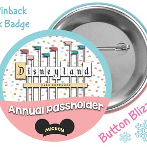 May include: A 3-inch pinback button with a pink background featuring the text "Annual Passholder" and a Mickey Mouse head with the word "Mickey" underneath. The top half of the button features a colorful illustration of the Disneyland park entrance with the text "Disneyland" and "Park Entrance".