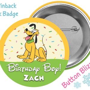 May include: A 3-inch pinback park badge featuring Pluto, the Disney cartoon dog, with the text "Birthday Boy! ZACH" on a green and yellow background. The badge has a metal pin on the back and a colorful confetti design.
