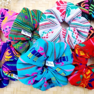 May include: Six colorful hair scrunchies with a woven pattern. The scrunchies are made of fabric and have a small tag that says "Ally Ren".