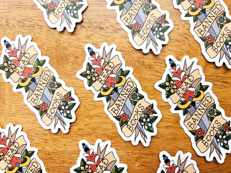 May include: A set of nine stickers featuring a stylised dagger with a banner reading "Read Banned Books". The dagger is decorated with flowers and the banner is in a vintage style.