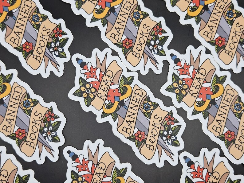 May include: A set of colourful stickers featuring a dagger and the words "Banned Books, Read" on a banner. The stickers are designed to look like traditional tattoo flash art.