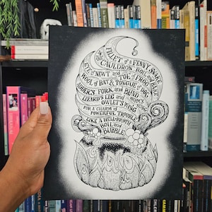 May include: A black and white illustration of a cauldron with text around it that reads "In the cauldron boil and bake, fillet of a fenny snake, eye of newt and toe of frog, wool of bat and tongue of dog, adder's fork and blind worm's sting, lizard's leg and owlet's wing, for a charm of powerful trouble, like a hell-broth boil and bubble."