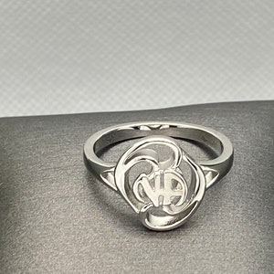 May include: A silver ring with a stylized design featuring a heart shape and a circle.