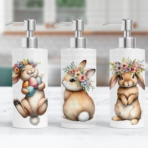 May include: Three white ceramic soap dispensers with bunny rabbit designs. Each dispenser features a different bunny rabbit with a floral crown and holding Easter eggs. The dispensers have silver pumps.
