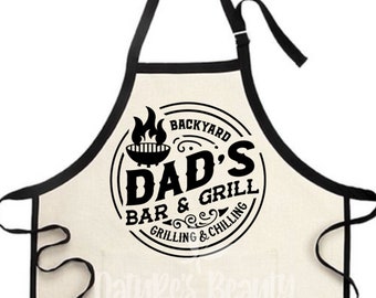May include: Black and white apron with a circle design that says "Backyard Dad's Bar & Grill Grilling & Chilling".