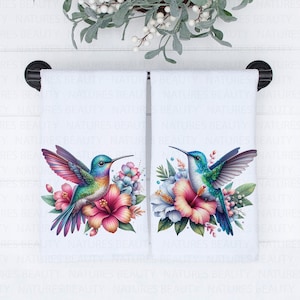 May include: Two white kitchen towels with a hummingbird and floral design. The hummingbirds are blue, green, and purple with long beaks. The flowers are pink, white, and green.