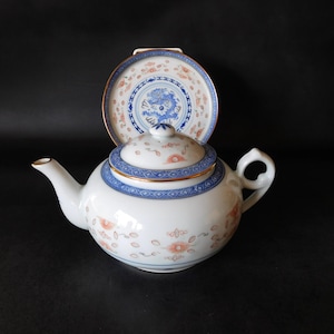 May include: White porcelain teapot with a matching lid and a small plate. The teapot and plate feature blue and orange floral and geometric patterns with gold trim. The plate has a central blue dragon design.