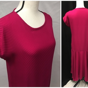 May include: A pink, short-sleeved dress with a diagonal striped pattern and a ruffled hem.