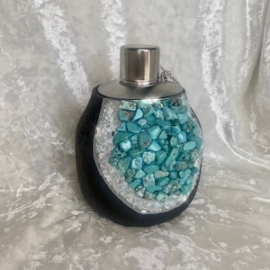 May include: A black and silver oil lamp with a turquoise stone design. The lamp has a silver lid and a chain attached to the lid.
