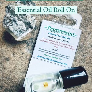 May include: A 4 ml roll-on bottle of peppermint essential oil with sweet almond oil, amber and green aventurine chips. The label reads "Peppermint - Essential Oil Roll-On Apply to pulse points. Sweet Almond Oil. Essential Oils of Peppermint Amber & Green Aventurine Chip 4 ml. External use only. Not FDA evaluated or approved. Not intended to treat, cure or prevent any disease or illness. Made in Sedalia, VA keithasartfulgarden.etsy.com"