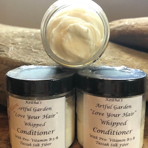 May include: Two 3.5 ounce jars of whipped conditioner labeled "Keitha's Artful Garden "Love Your Hair" Whipped Conditioner" with the ingredients "With Pro-Vitamin B-5 & Tussah Silk Fiber" and "Made in Sedalia, VA".
