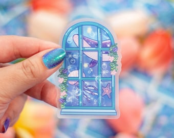 May include: A whimsical sticker featuring a blue window with an underwater scene. A purple whale, jellyfish, and starfish are visible. The window is adorned with flowers and bubbles. The sticker has a clear, transparent background.