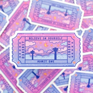 May include: A pink and blue ticket sticker with the text "Believe in Yourself" and "Admit One". The ticket has a starry night sky with clouds and a crescent moon.