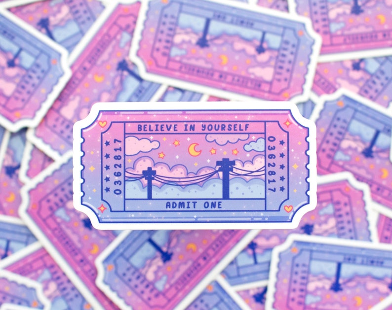 May include: A pink and blue ticket sticker with the text "Believe in Yourself" and "Admit One". The ticket has a starry night sky with clouds and a crescent moon.