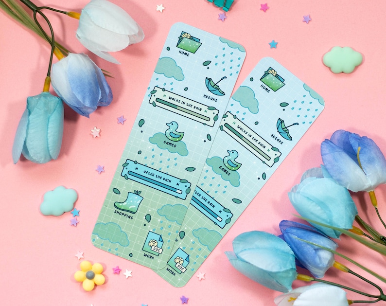 May include: Two blue and green illustrated bookmarks with a rainy day theme. The bookmarks feature a duck, an umbrella, a rain cloud, and a boot. The text on the bookmarks includes "Home", "Books", "Games", "Shopping", "Work", and "After the Rain".