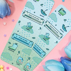 May include: Two blue and green bookmarks with a rain theme. The bookmarks feature a variety of illustrations, including raindrops, clouds, umbrellas, and a duck. The bookmarks also have a slider with the text "Walks in the Rain" and "After the Rain".