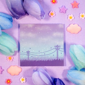 May include: Purple and blue pastel colored paper with a purple card with a drawing of a night sky with stars and power lines. The card is surrounded by pastel colored flowers and clouds.