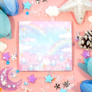 May include: A pink and blue pastel notepad with a rainbow, clouds, and trees design. The notepad is surrounded by glitter, stars, and other decorative elements.