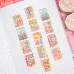 May include: A journal page with decorative washi tape strips featuring colourful illustrations of rooms, clouds, and objects. Two rolls of matching washi tape are visible. The tape has a pink and green colour scheme.