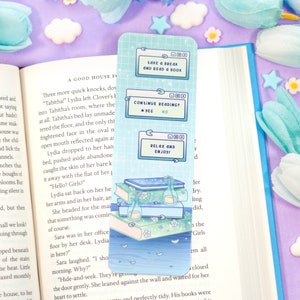 May include: A blue and white bookmark with a stack of books, a bottle, and flowers. The bookmark features a digital screen with the text "Lake & Break and Read & Book", "Continue Reading? Yes No", and "Relax and Enjoy!"