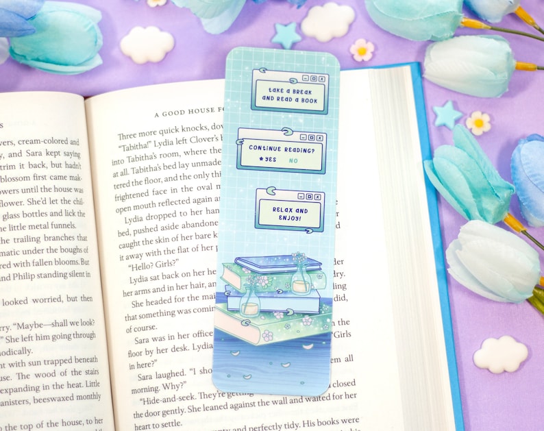 May include: A blue and white bookmark with a stack of books, a bottle, and flowers. The bookmark features a digital screen with the text "Lake & Break and Read & Book", "Continue Reading? Yes No", and "Relax and Enjoy!"