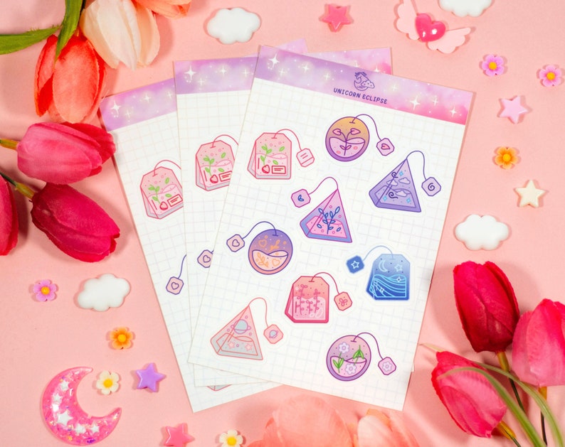 May include: A set of 10 colorful tea bag stickers with a whimsical unicorn theme. The stickers feature various designs, including teacups, stars, and moons. The stickers are printed on a white background with a subtle grid pattern. The text "Unicorn Eclipse" is printed at the top of the sheet.