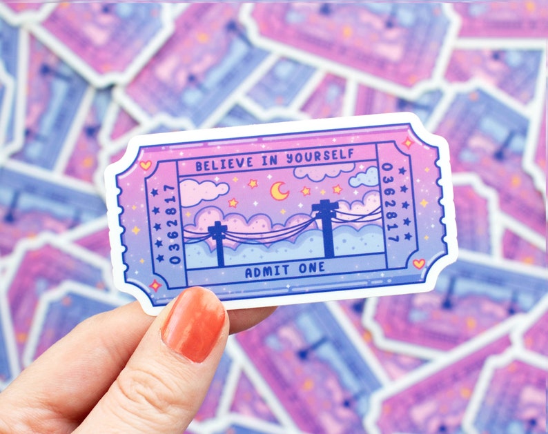 May include: A pink and purple ticket with the text "Believe in Yourself" and "Admit One". The ticket has a starry night sky with a crescent moon and power lines.