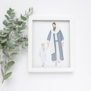 May include: A framed illustration of a man in a blue robe and a white scarf holding the hand of a young boy in a white suit. The illustration is in a white frame.