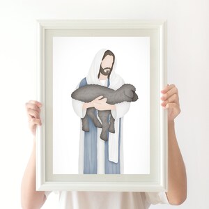 Puede incluir: Una ilustraci&oacute;n enmarcada de Jes&uacute;s sosteniendo un cordero en sus brazos. Jes&uacute;s lleva una t&uacute;nica azul y una chal blanco. El fondo es blanco.