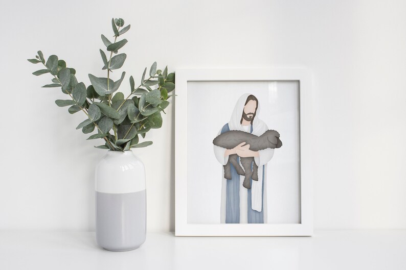 Puede incluir: Una impresi&oacute;n enmarcada en blanco de una ilustraci&oacute;n de acuarela de Jes&uacute;s sosteniendo un cordero. La ilustraci&oacute;n es de estilo minimalista con un fondo blanco.