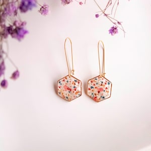 Collier et boucles d'oreilles pendantes avec de fleurs séchées multicolore en résine. Ensemble de bijoux doré en forme de hexagonale. Boucles d'oreilles