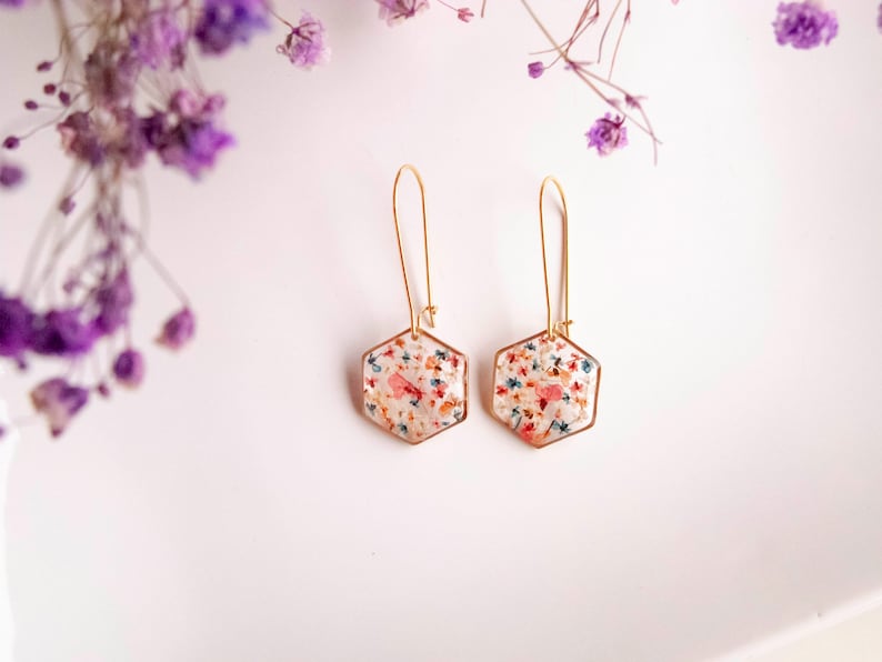 Collier et boucles d'oreilles pendantes avec de fleurs séchées multicolore en résine. Ensemble de bijoux doré en forme de hexagonale. Boucles d'oreilles